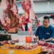 Açougueiro trabalhando em balcão de carnes.
