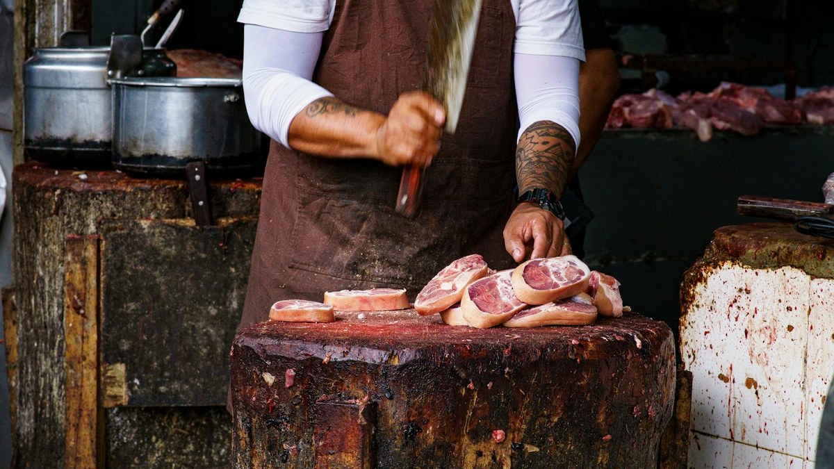 Açougueiro preparando carne em balcão de trabalho.