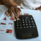 Pessoa usando calculadora sobre documentos financeiros e gráficos