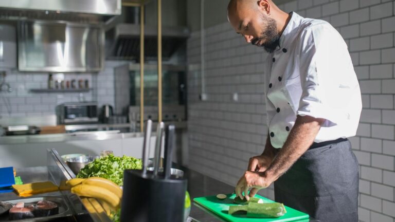 Profissional cortando legumes em cozinha profissional