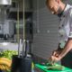 Profissional cortando legumes em cozinha profissional