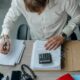 Profissional analisando documentos contábeis com calculadora