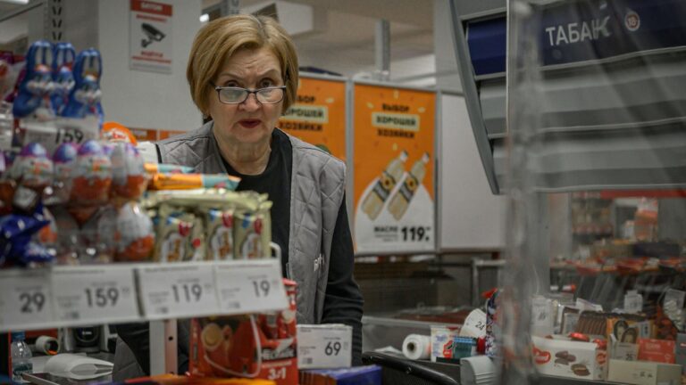 Operadora de caixa atendendo cliente em supermercado