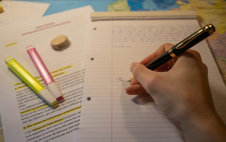 Pessoa escrevendo em caderno com caneta durante estudo de redação para o ENEM