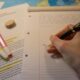 Pessoa escrevendo em caderno com caneta durante estudo de redação para o ENEM