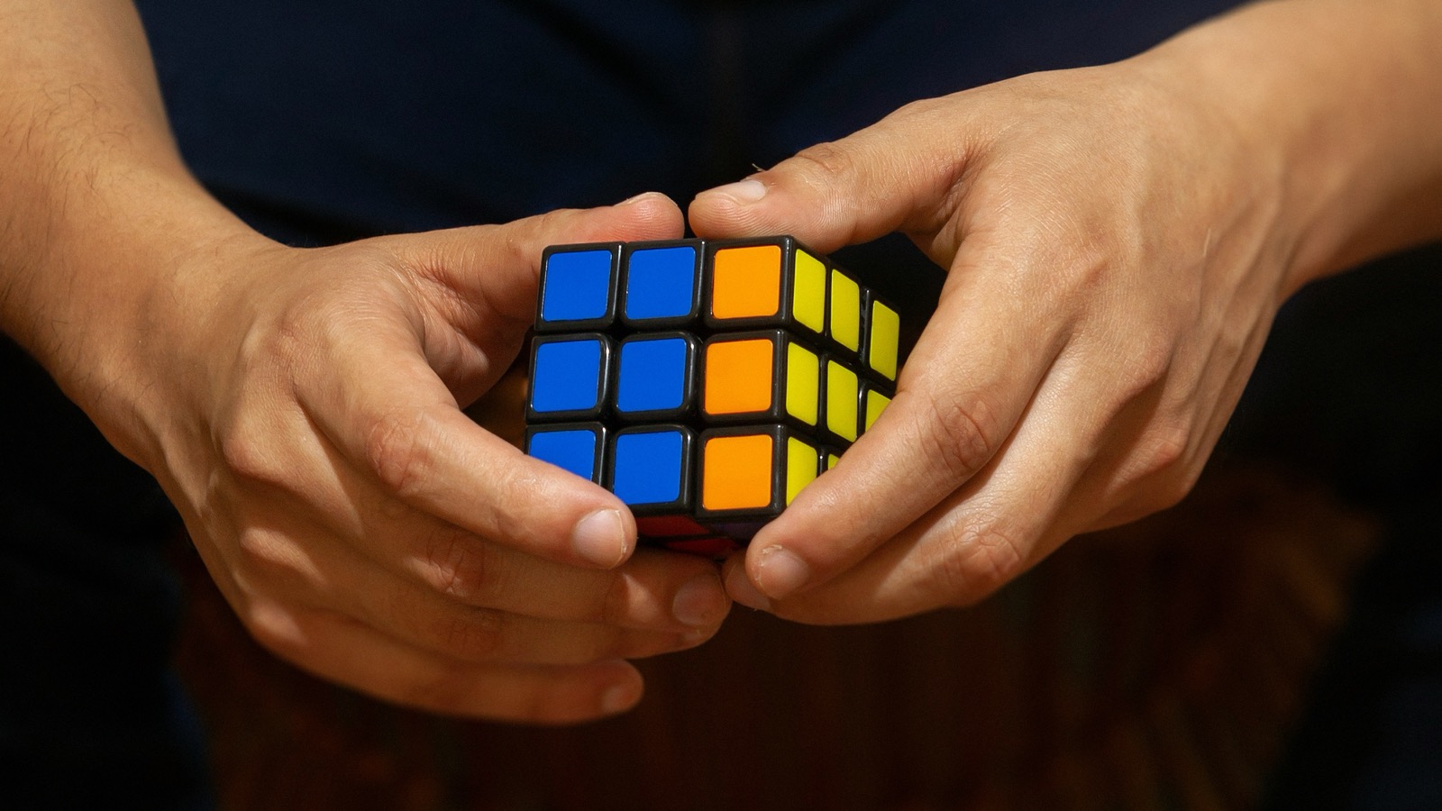 Mãos resolvendo cubo mágico como representação de raciocínio lógico e resolução de problemas para concursos públicos