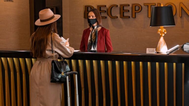 Recepcionista atendendo cliente em balcão de recepção.