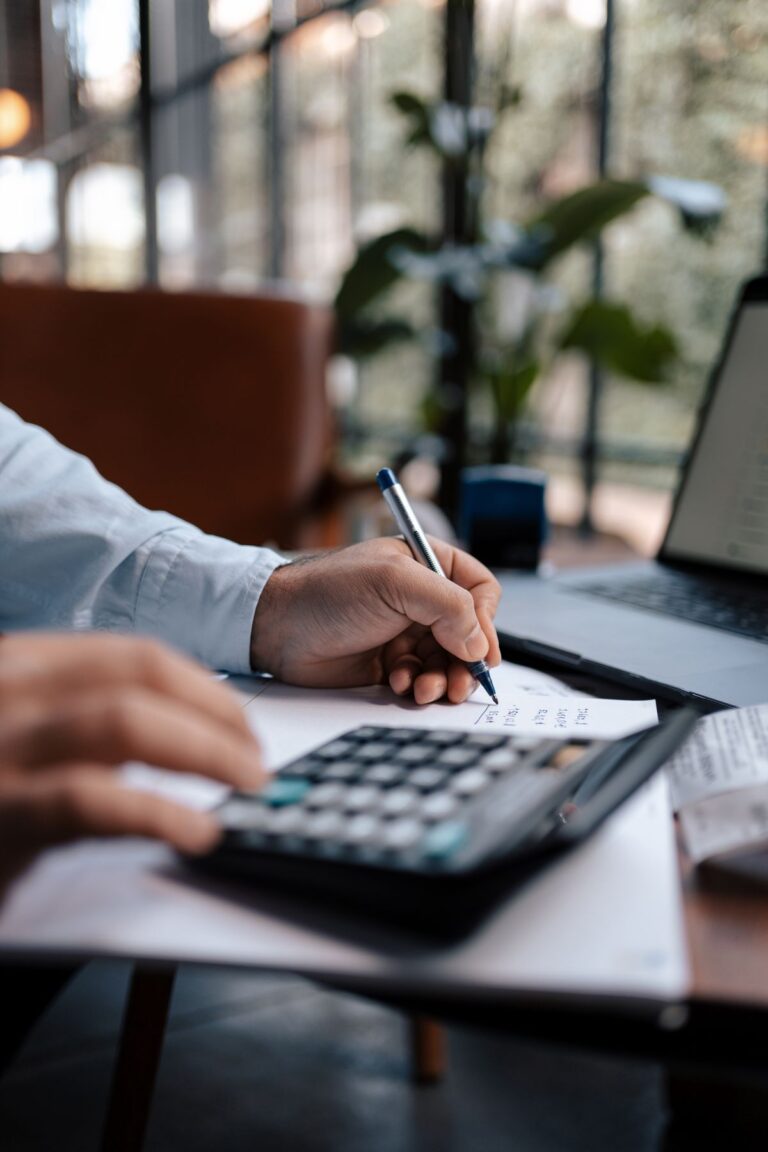 Pessoa usando calculadora e anotações financeiras, representando curso de investimentos para iniciantes.