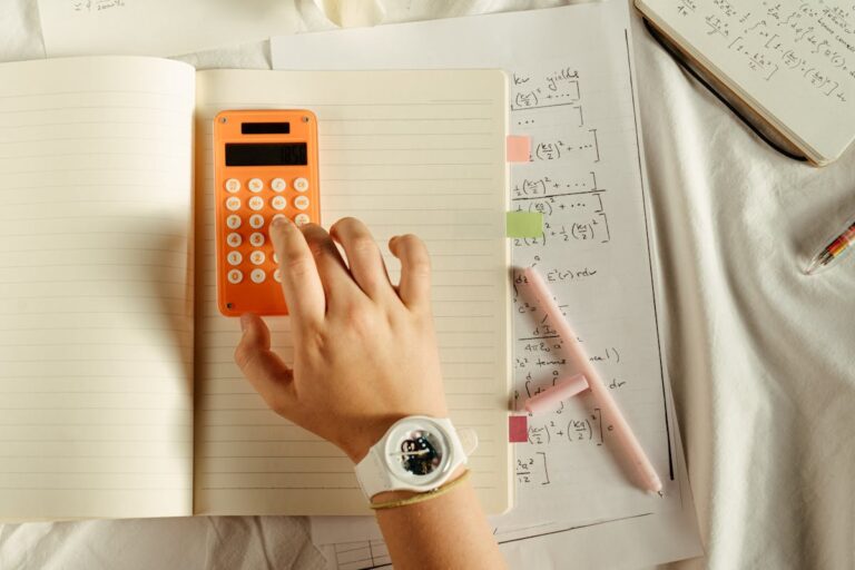 Estudante usando calculadora e caderno, representando curso de educação financeira para jovens.