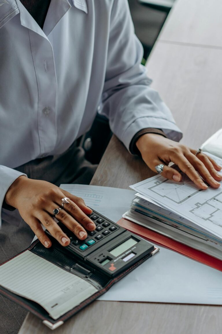 Pessoa usando calculadora sobre documentos financeiros, representando curso de educação financeira pessoal.