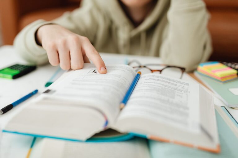 Estudante lendo livro e fazendo anotações, representando preparação de inglês para o ENEM.