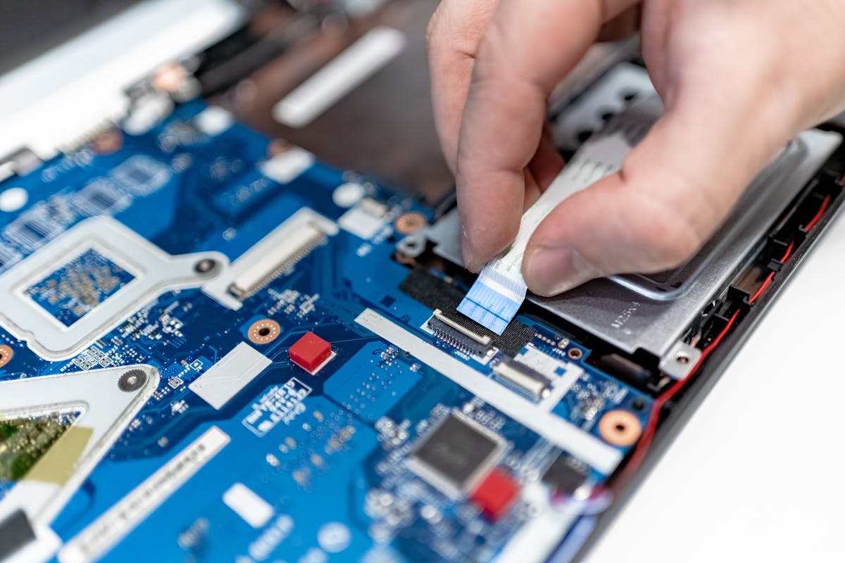Mãos reparando componentes internos de computador, representando curso de montagem e manutenção de computadores.