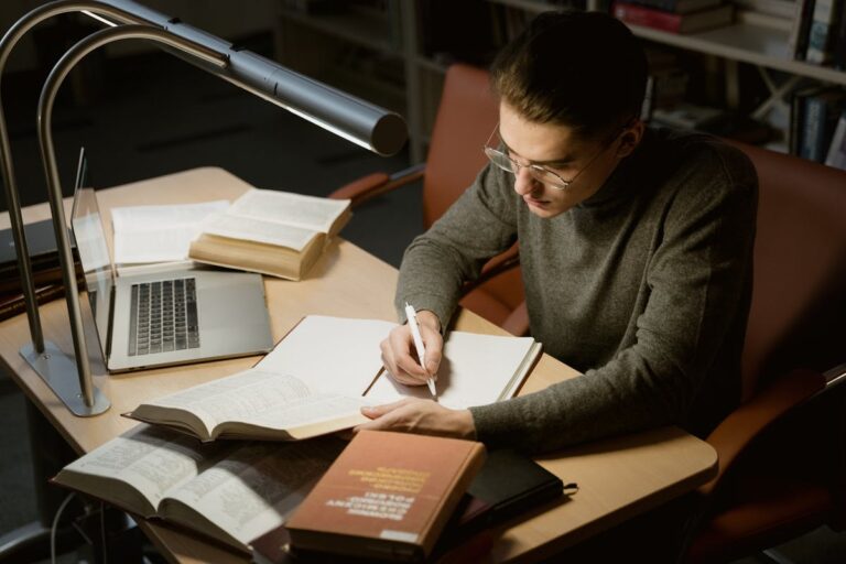 Pessoa estudando com livros e caderno, representando curso de português para concursos.