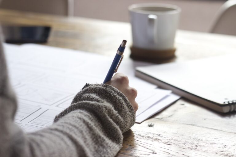 Estudante escrevendo em material de estudo para prova