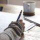 Estudante escrevendo em material de estudo para prova
