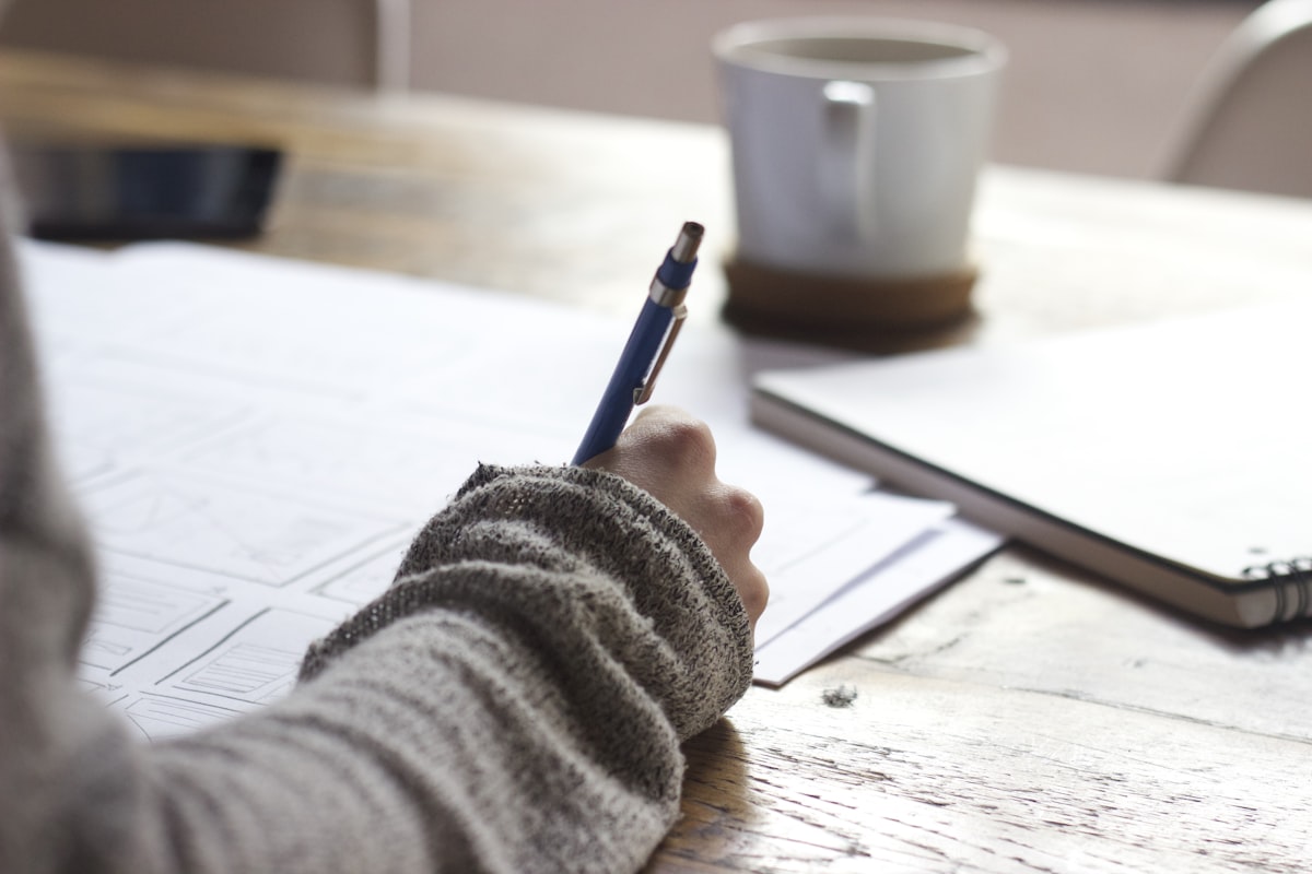 Estudante escrevendo em material de estudo para prova