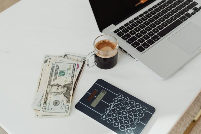 Mesa com dinheiro, calculadora e notebook para organização de orçamento familiar