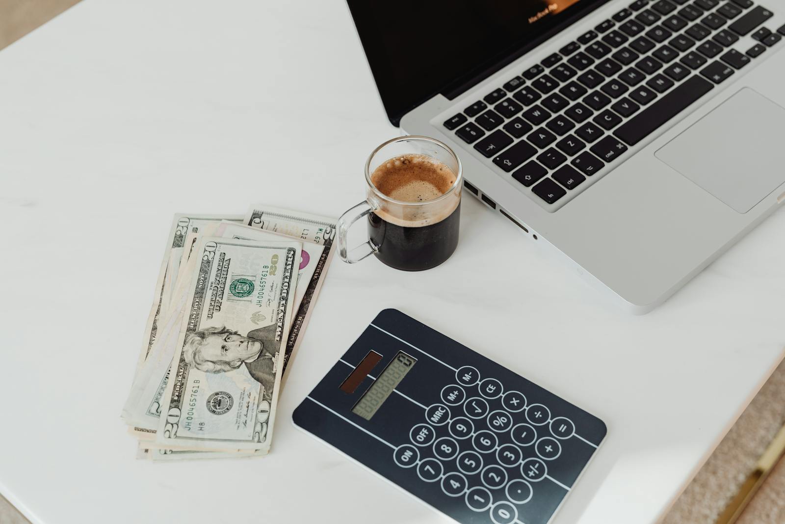 Mesa com dinheiro, calculadora e notebook para organização de orçamento familiar