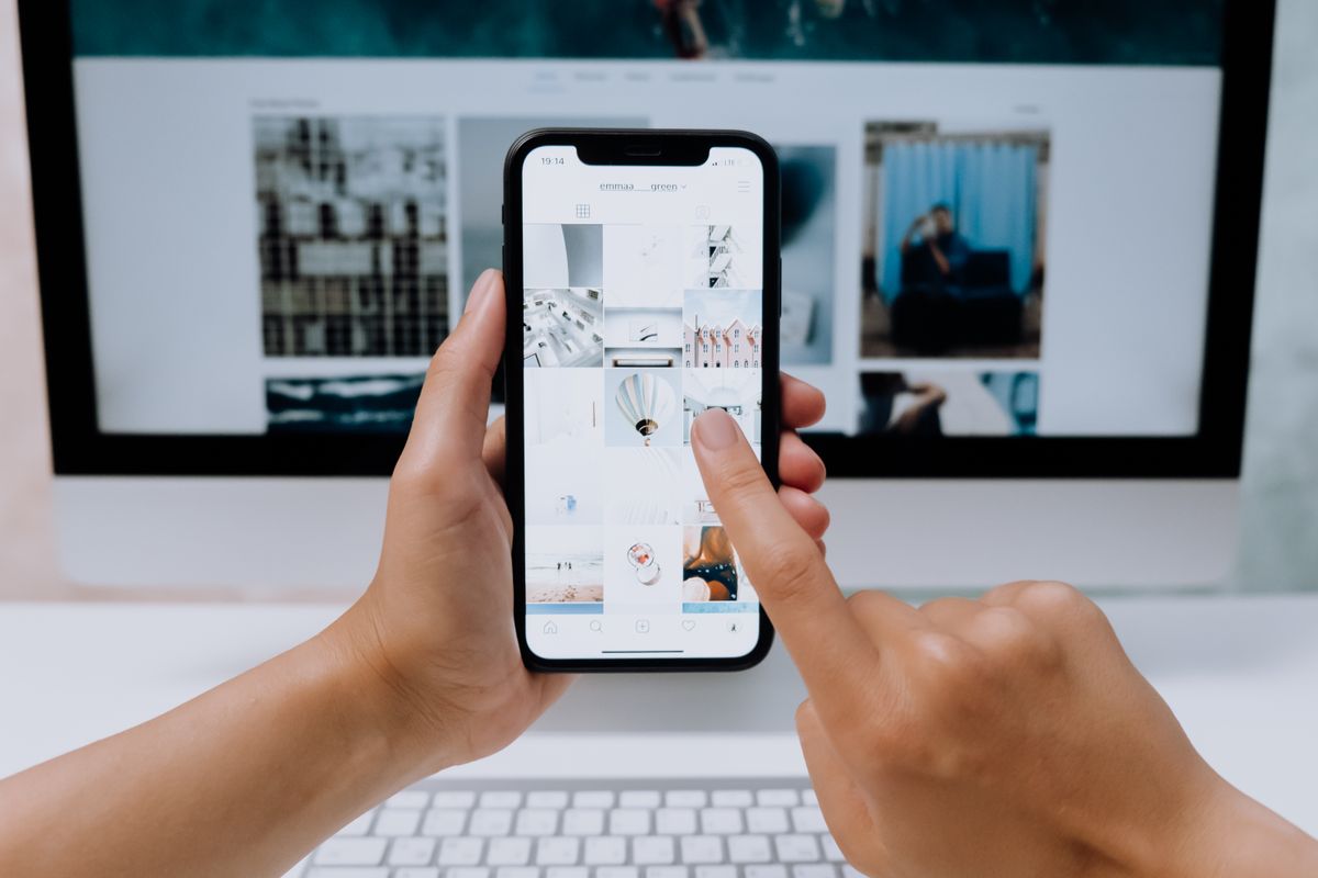 Pessoa usando smartphone com rede social em ambiente de trabalho, representando marketing digital e redes sociais.