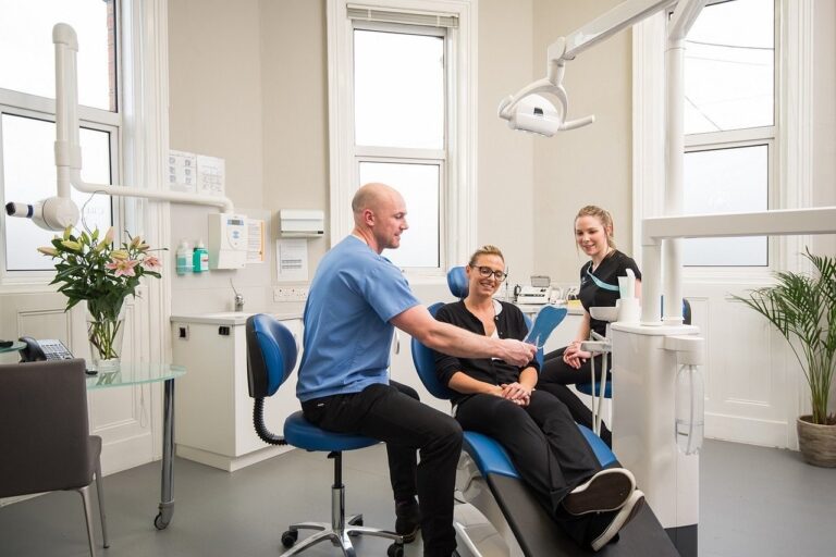 Dentista atendendo paciente em clínica odontológica, representando curso gratuito de saúde bucal na atenção primária.