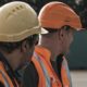 Trabalhadores usando capacete, colete e equipamentos de proteção em ambiente de trabalho